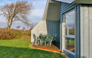 Ein Gebäude mit einer Terrasse, komplett mit Tisch und Stühlen.