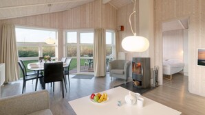 A modern room with a dining area, a fireplace, and a bed. - Friedrichskoog-Strandpark 16 (Friedrichskoog)