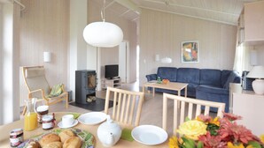 Un salón acogedor con un sofá, televisión y comedor con mesa dispuesta para el desayuno.