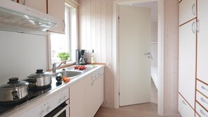 Una cocina compacta con estufa, lavamanos y armarios.