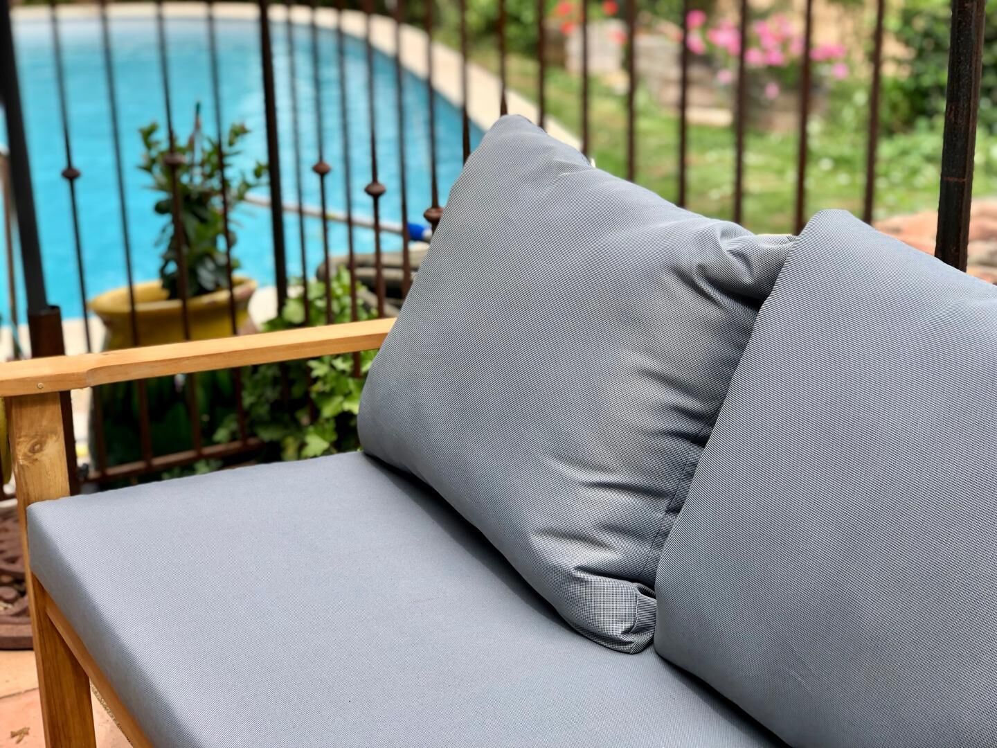 Area relax esterna con sedute imbottite grigie, vista su piscina e giardino.