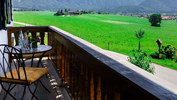 A balcony with a table and chairs overlooking a green field and mountains. - Vacation apartment Sunnseitn for 4 persons, 2 bedrooms, 2 balconies, 54 sqm (Inzell)