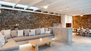 Un espace de vie moderne avec un mur en pierre, un canapé gris agrémenté de coussins, une table basse en bois et une cheminée.