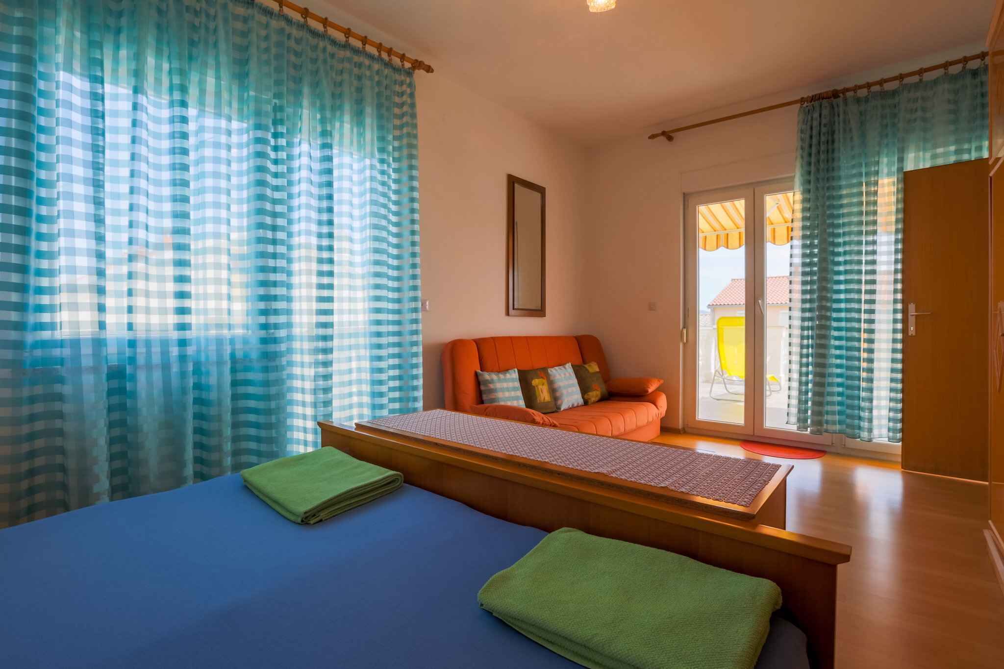 Una habitación con cama, sofá y vistas al exterior por una puerta corredera.