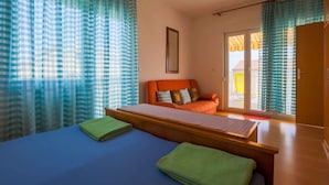 Ein Zimmer mit einem Bett, einem Sofa und Blick durch eine Schiebetür ins Freie.