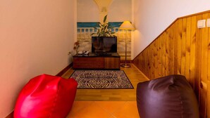 Ein Flur mit einer Holzwand, einem zebra-muster Teppich, einer roten und schwarzen Lederbank, einer Topfpflanze, einer Lampe und einem Fernseher auf einer Holzkommode.