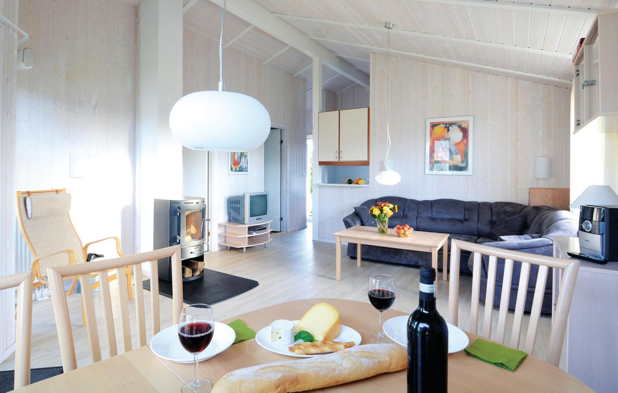 Uma sala de estar moderna com lareira, sofá, mesa de jantar com comida e vinho, e uma televisão.