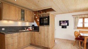 A kitchen with wooden cabinets, a built-in oven, and a dining area with a wooden table and chairs. - Vacation apartment Himmelsstiang for 5 persons, 2 bedrooms, balcony, 57 sqm (Inzell)