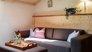 A cozy living room with a grey sofa, a wooden coffee table with drinks, and a plant on a shelf. - Vacation apartment Himmelsstiang for 5 persons, 2 bedrooms, balcony, 57 sqm (Inzell)