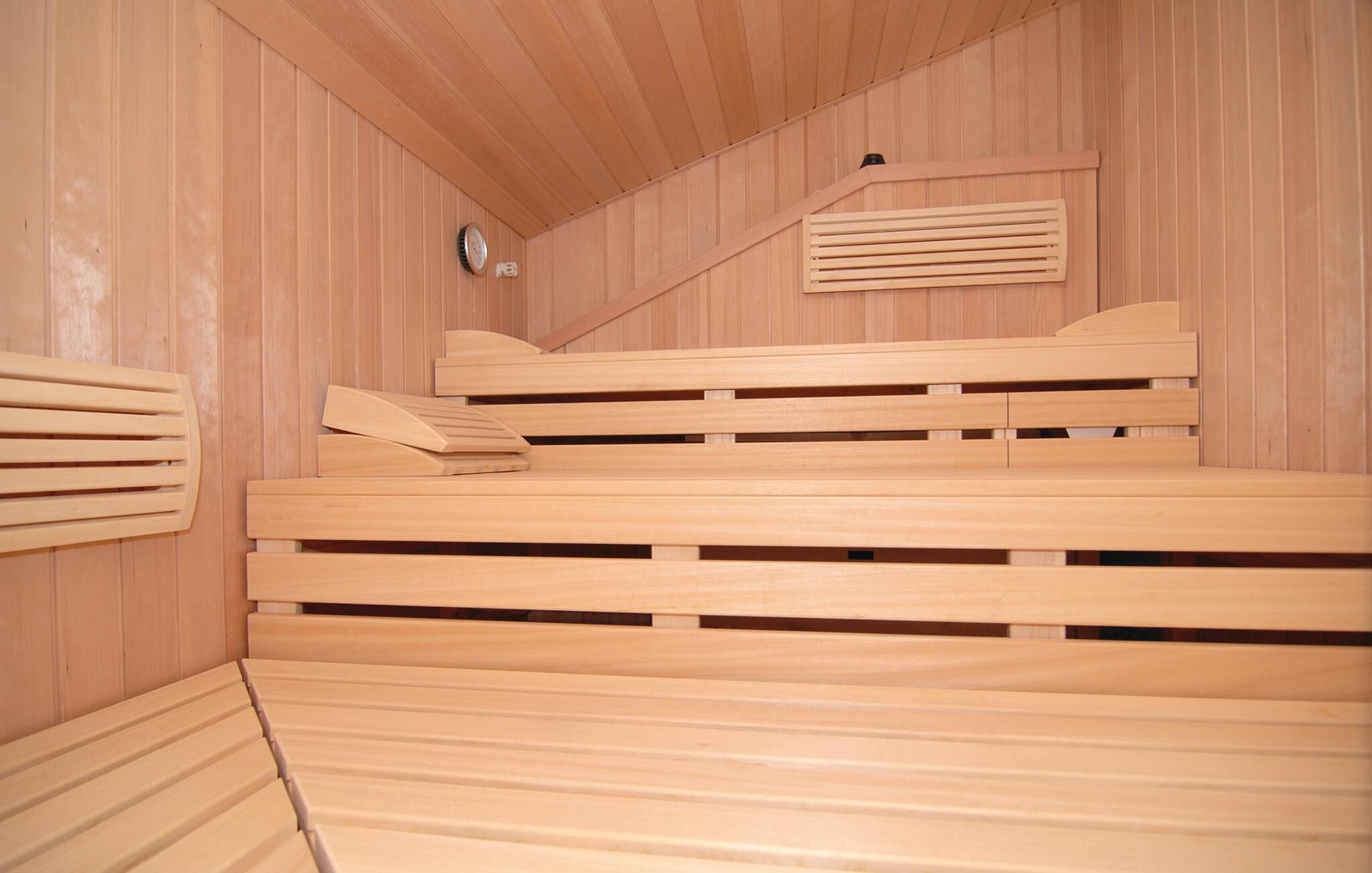 Una sala de sauna con bancos de madera y techo inclinado.
