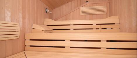 Una sala de sauna con bancos de madera y techo inclinado.