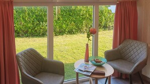 A room with two armchairs, a small table, and a window with curtains.