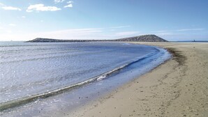 A sandy beach with gentle waves, a rocky outcrop in the distance, and a clear sky. - 1 bedroom awesome home in Calvisson (Calvisson)