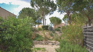 A garden with various plants and trees, a stone wall, and a wooden fence. - 1 bedroom awesome home in Calvisson (Calvisson)
