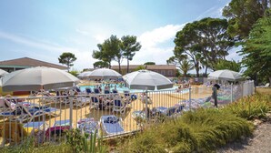 A poolside area with sun loungers and umbrellas, surrounded by trees and buildings. - 1 bedroom awesome home in Calvisson (Calvisson)