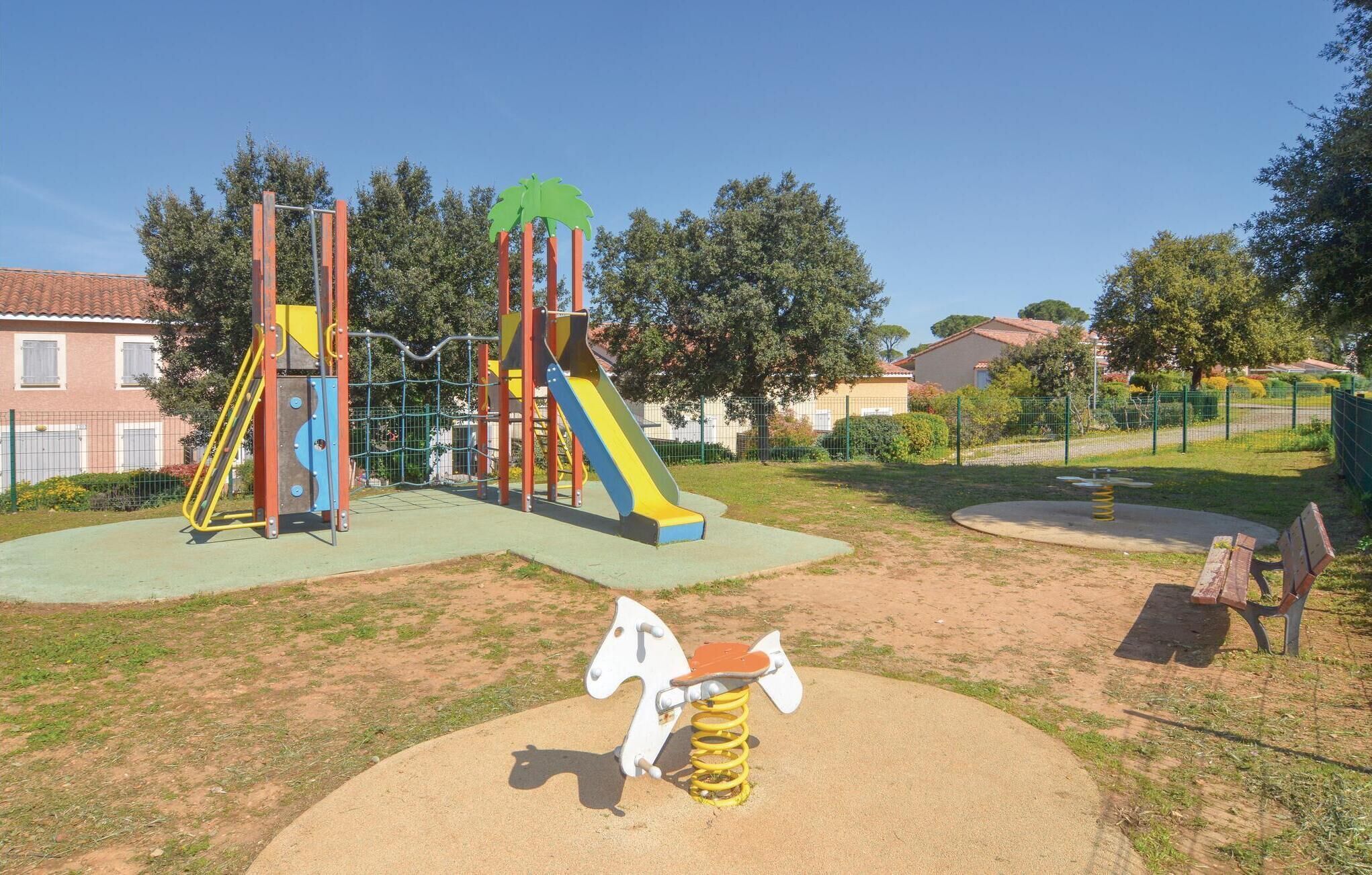 A playground with a slide, climbing structures, and a merry-go-round.
