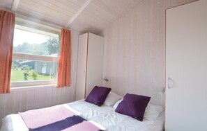 Cozy retreat with a single bed, featuring a white mattress and two pillows, and a window with a view of the outdoors.