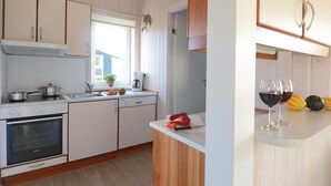Une cuisine avec des meubles de rangement en bois, un four encastré, un évier et une fenêtre.