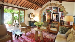 A cozy living room with wooden furniture, a stone archway, and a view of the garden. - Stunning private villa with WIFI, private pool, TV, patio and panoramic view, close to Lucca (Santo Stefano)