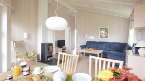Una sala de estar acogedora con un sofá, una mesa de comedor con artículos para el desayuno, un televisor y una chimenea.