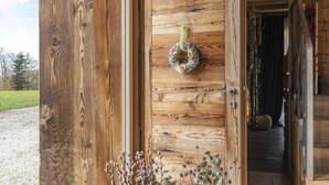 A wooden door with a wreath hanging on it, a keyhole, and a small plant at the bottom. - Casera Cornolera (Chies d´Alpago)