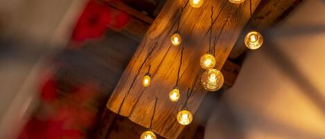 A staircase with a wooden railing and a ceiling with exposed beams and hanging light fixtures.