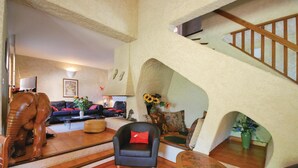Uma sala de estar ampla, com escada, sofá, mesa de centro e uma escultura decorativa de elefante.