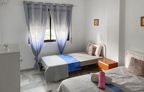 Ein Schlafzimmer mit zwei Betten, einem Nachttisch, einem Kleiderschrank und einem Fenster mit Vorhängen.