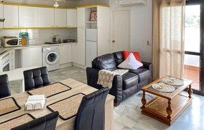 Un espace de vie compact comprenant une cuisine, un coin repas et un espace détente.
