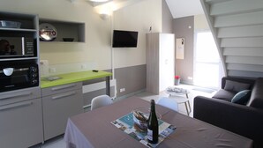 A compact kitchen with a microwave, toaster, and a green countertop. A dining table with a bottle and a menu is set up.