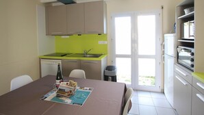 A compact kitchen with a sink, a dishwasher, and a dining area with a table set for two.