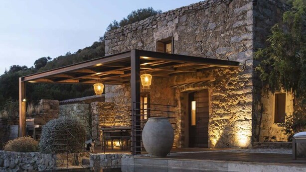 Un bâtiment en pierre doté d’une piscine, d’un espace extérieur aménagé et d’une pergola illuminée.