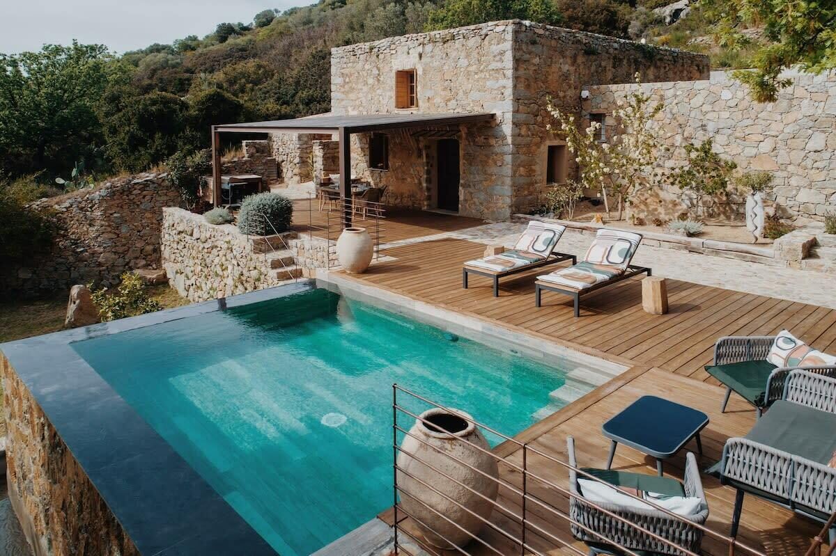 Une maison en pierre avec une piscine et un espace extérieur aménagé pour se détendre.