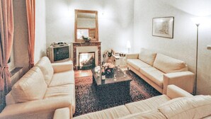 Una sala de estar con chimenea, dos sofás, una mesa de centro y un televisor.
