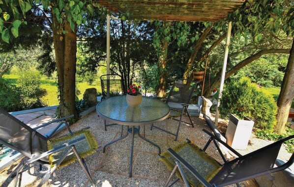 Relax in a serene outdoor space surrounded by lush greenery and a wooden pergola.