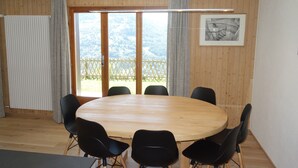 A round wooden table with six black chairs in a room with wooden walls and large windows. - Greppons N 002 - MOUNTAIN apartment 9 pers (Veysonnaz)