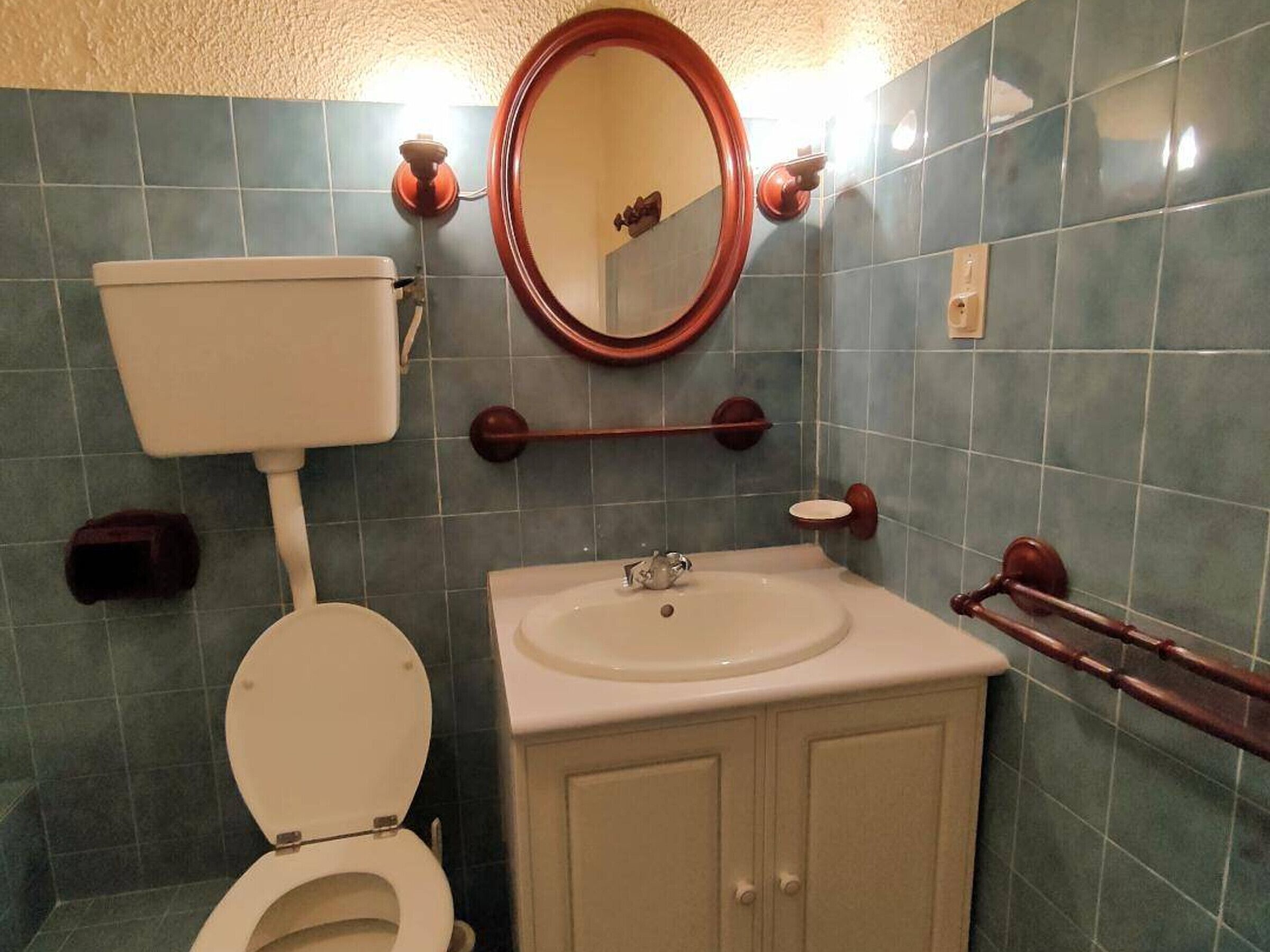 A bathroom with a toilet, sink, and mirror.
