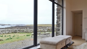 A room with large windows offering a view of a rocky landscape and a body of water. - 3 bedroom accommodation in Roag, Isle of Skye (Roag, Isle of Skye)