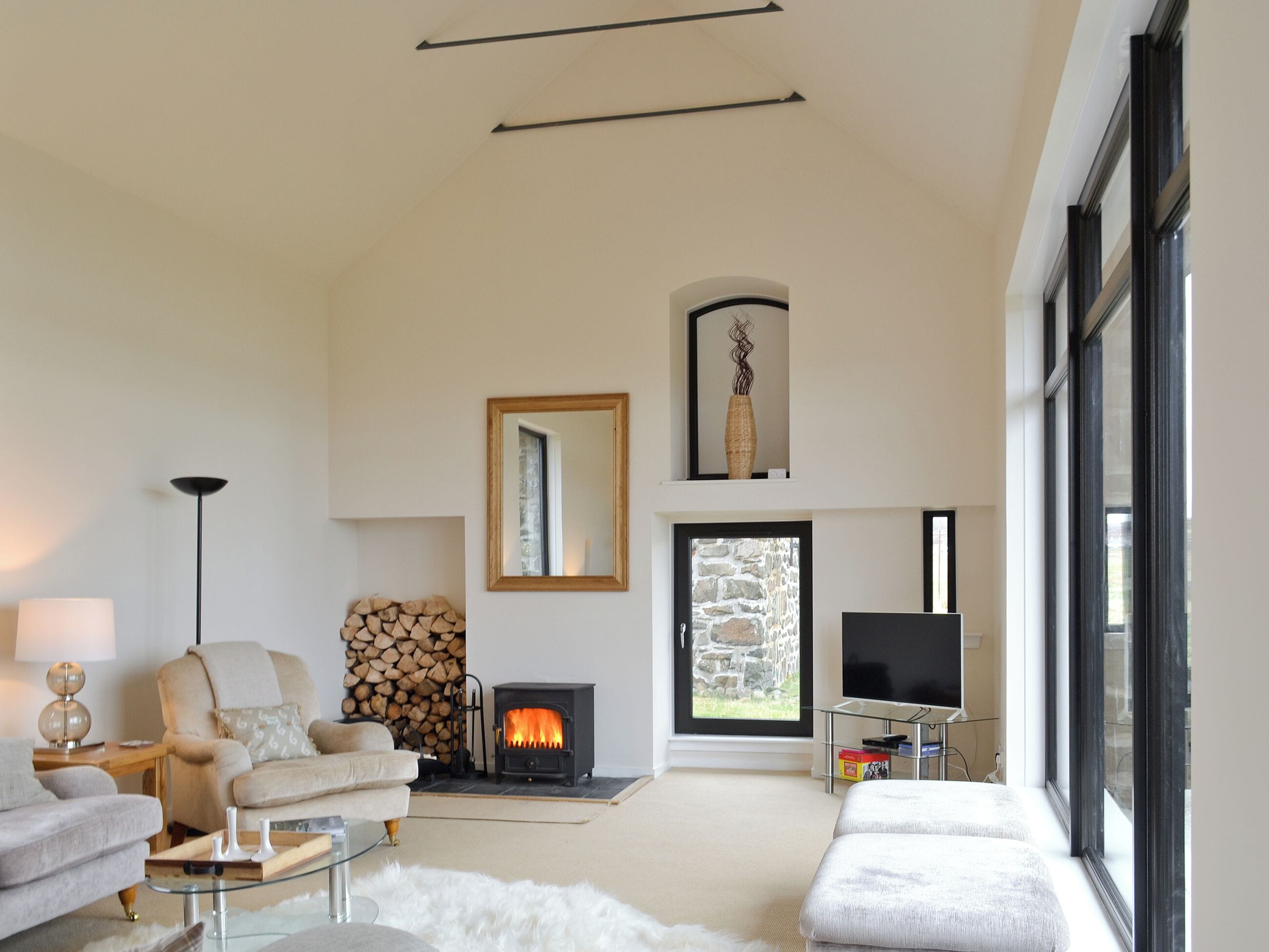 Un salon moderne avec une cheminée, un canapé, un fauteuil et un téléviseur.