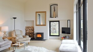 A modern living room with a fireplace, a sofa, a chair, and a TV. - 3 bedroom accommodation in Roag, Isle of Skye (Roag, Isle of Skye)