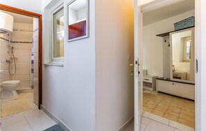 Et badeværelse med bruser, toilet og spejl.