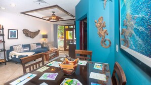 Uma área de refeições com uma mesa posta para dois, rodeada por paredes azuis com obras de arte.