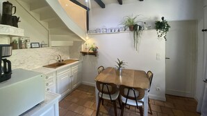 Una cocina con una mesa y sillas de madera, un fregadero y una escalera que sube a un nivel superior.