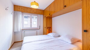 Une chambre avec deux lits, un lambris en bois, une fenêtre avec des rideaux et un luminaire suspendu.