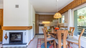 Une cuisine moderne avec des meubles en bois, un four encastré et un coin repas comprenant une table et des chaises en bois.