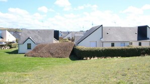 A row of modern houses with sloped roofs, a grassy area, and a hedge.