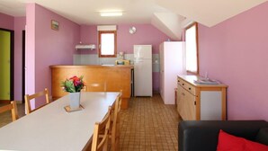 A compact kitchen with a dining area, a refrigerator, a microwave, and a small cabinet.