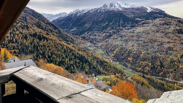 Un paysage montagneux avec une vallée, une structure en bois et un petit bâtiment.
