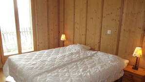 Une chambre à coucher avec un grand lit, des murs en bois et deux lampes de chevet.