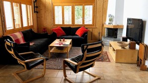 Un intérieur chaleureux en bois, avec un canapé, deux fauteuils à bascule, une table basse et une cheminée.